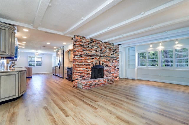 1670 Fox Rd, Clearwater, FL 33764 - unfurnished living room with beamed ceiling, a brick fireplace, baseboards, light wood finished floors, and ceiling fan
