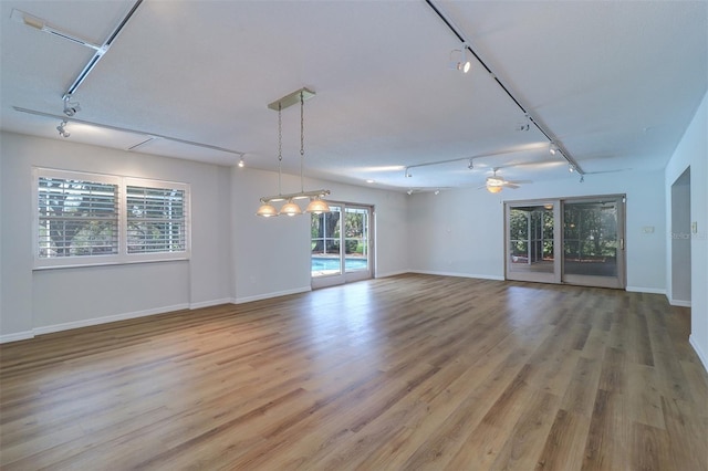 1670 Fox Rd, Clearwater, FL 33764 - unfurnished living room with rail lighting, ceiling fan, light wood-style floors, and baseboards
