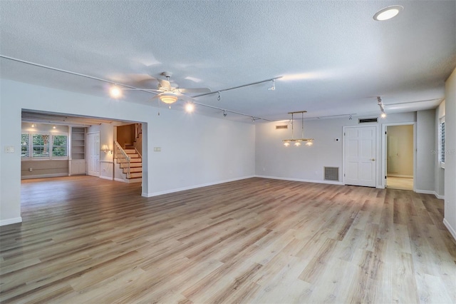 1670 Fox Rd, Clearwater, FL 33764 - unfurnished living room with stairs, a textured ceiling, light wood-type flooring, and track lighting