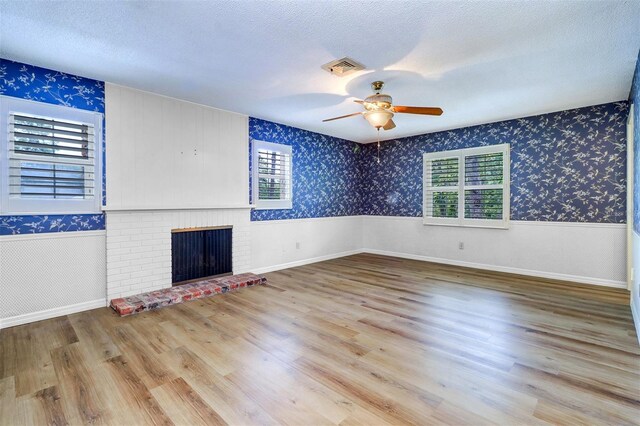 1670 Fox Rd, Clearwater, FL 33764 - unfurnished living room featuring healthy amount of natural light, a fireplace, wallpapered walls, a textured ceiling, and a ceiling fan