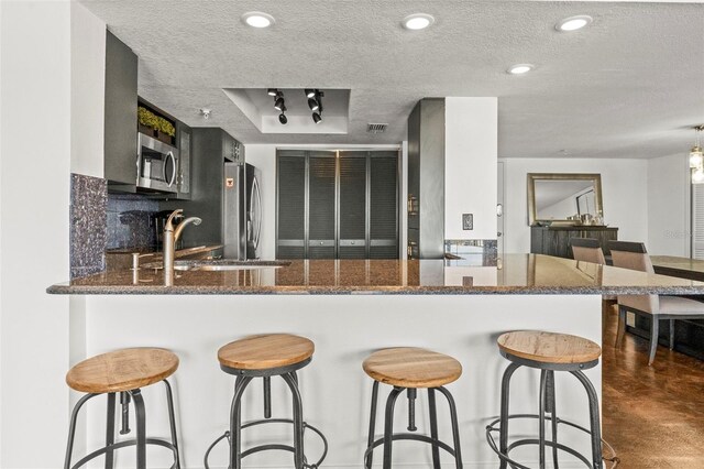 7432 Sunshine Skyway Ln S Unit 402, Saint Petersburg, FL 33711 - kitchen featuring stainless steel appliances, a sink, a textured ceiling, a kitchen breakfast bar, and dark stone countertops