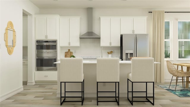 18477 Serene Lake Loop, Lutz, FL 33548 - kitchen with appliances with stainless steel finishes, wall chimney range hood, white cabinetry, light wood-style floors, and a center island