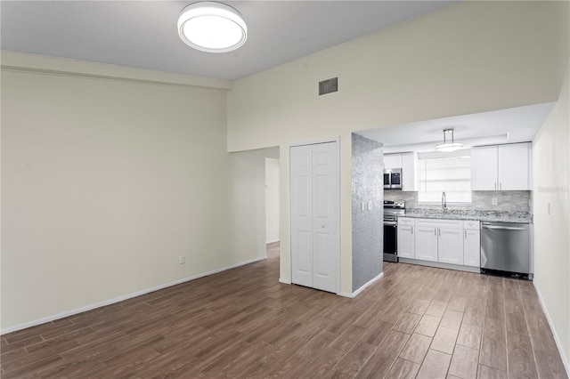 13046 Leverington St, Tampa, FL 33624 - kitchen with stainless steel appliances, dark wood-style flooring, a sink, white cabinetry, and a high ceiling