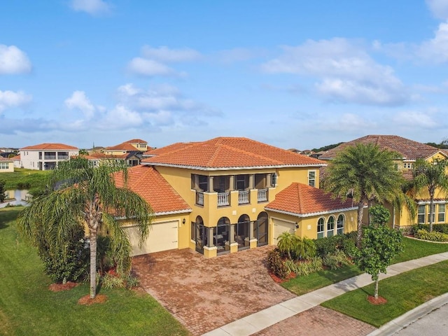 1140 Terralago Way, Kissimmee, FL 34746 - mediterranean / spanish home with a balcony, a tiled roof, decorative driveway, stucco siding, and a front lawn