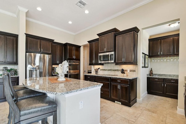 1140 Terralago Way, Kissimmee, FL 34746 - kitchen with stainless steel appliances, light stone counters, decorative backsplash, a center island, and crown molding
