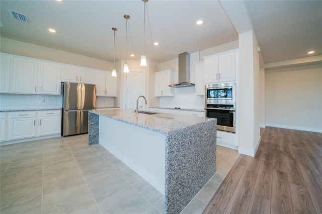 8834 Sanders Tree Loop, Wesley Chapel, FL 33545 - kitchen featuring appliances with stainless steel finishes, wall chimney range hood, a sink, white cabinetry, and backsplash