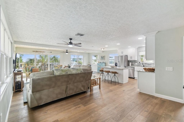 3285 Minnow Creek Dr, Hernando Beach, FL 34607 - living room with a textured ceiling, light wood-style floors, a ceiling fan, and recessed lighting