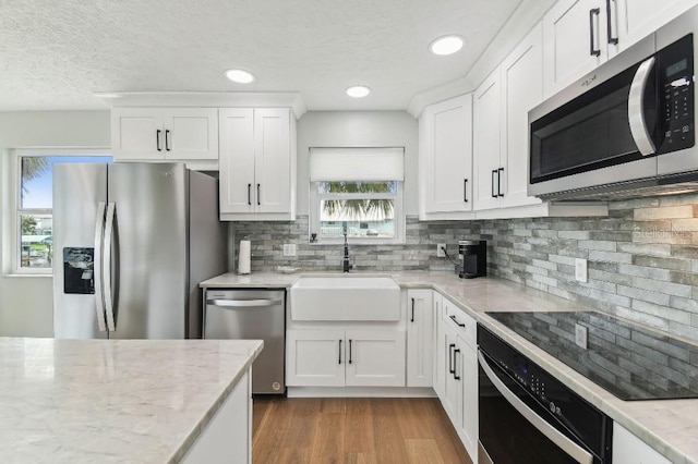 3285 Minnow Creek Dr, Hernando Beach, FL 34607 - kitchen featuring black appliances, a sink, white cabinets, decorative backsplash, and a textured ceiling