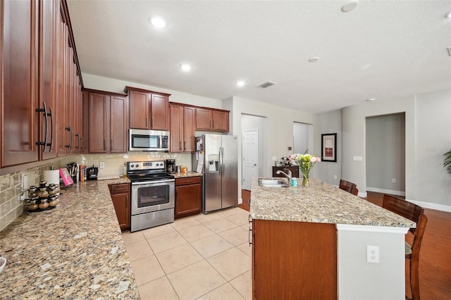 11314 American Holly Dr, Riverview, FL 33578 - kitchen with appliances with stainless steel finishes, a sink, backsplash, a kitchen island with sink, and recessed lighting