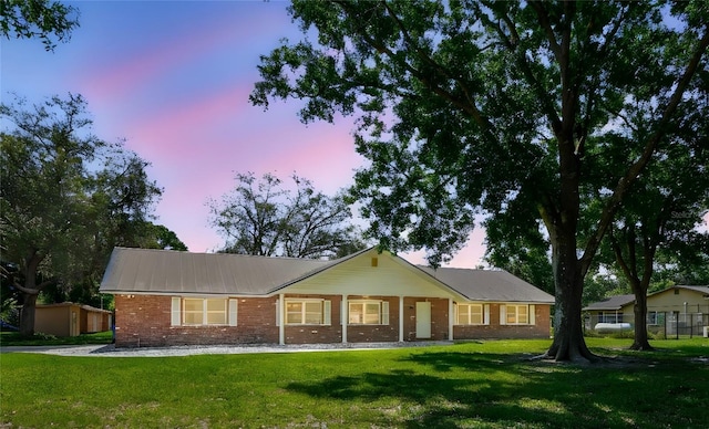 17801 Simmons Rd, Lutz, FL 33548 - back of house at dusk featuring a yard, brick siding, and metal roof