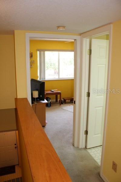 9722 Indian Key Trl Unit 116, Seminole, FL 33776 - hallway with carpet, a textured ceiling, a desk, and baseboards