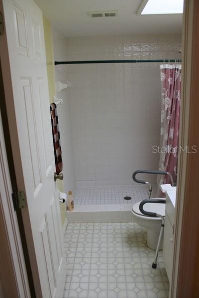 9722 Indian Key Trl Unit 116, Seminole, FL 33776 - bathroom featuring a shower stall, tile patterned floors, toilet, and vanity