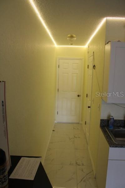 9722 Indian Key Trl Unit 116, Seminole, FL 33776 - hallway with baseboards, light marble finish floors, and a sink