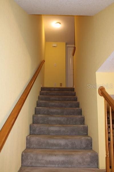 9722 Indian Key Trl Unit 116, Seminole, FL 33776 - stairway featuring a textured ceiling