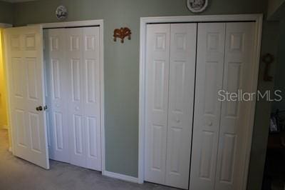9722 Indian Key Trl Unit 116, Seminole, FL 33776 - unfurnished bedroom featuring baseboards, carpet flooring, and two closets