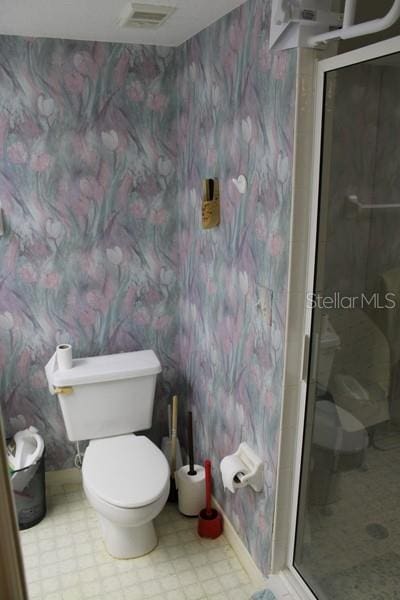 9722 Indian Key Trl Unit 116, Seminole, FL 33776 - full bathroom with wallpapered walls, toilet, tile patterned floors, a shower stall, and baseboards