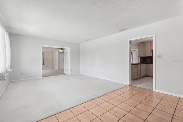 1212 Blake Ave, Auburndale, FL 33823 - spare room with light carpet, a textured ceiling, light tile patterned flooring, a ceiling fan, and baseboards
