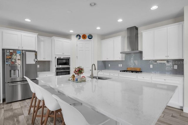 12650 Shetland Walk Dr, Lithia, FL 33547 - kitchen featuring appliances with stainless steel finishes, wall chimney exhaust hood, a sink, a spacious island, and white cabinets