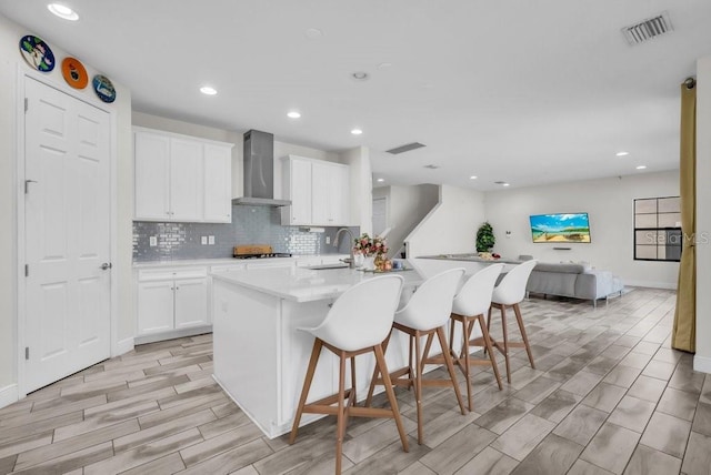 12650 Shetland Walk Dr, Lithia, FL 33547 - kitchen with wall chimney exhaust hood, a breakfast bar, backsplash, recessed lighting, and white cabinetry