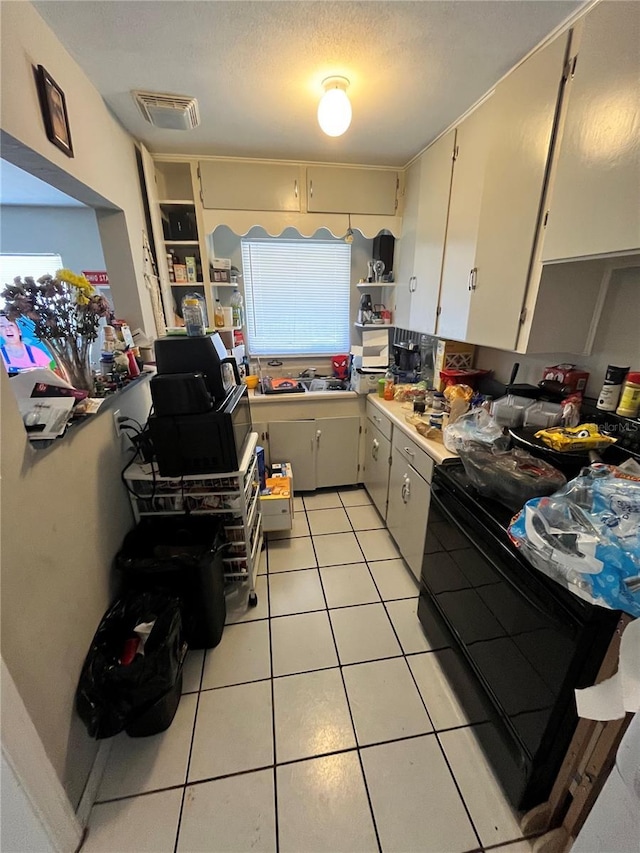 1708 28th St W, Bradenton, FL 34205 - kitchen with black range with electric cooktop, light tile patterned floors, light countertops, and open shelves