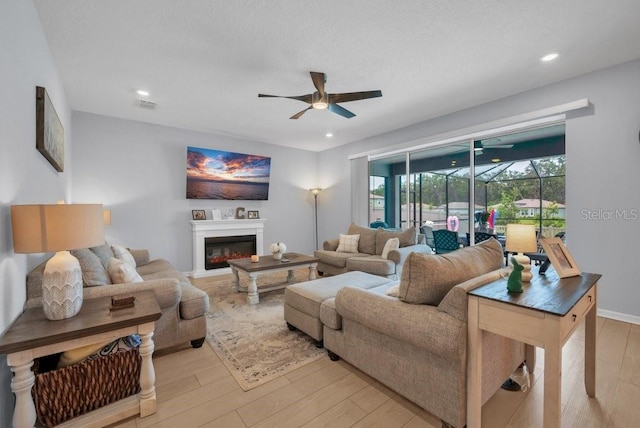 2781 Dolores Home Ave, Valrico, FL 33594 - living area with a ceiling fan, light wood finished floors, a glass covered fireplace, and recessed lighting