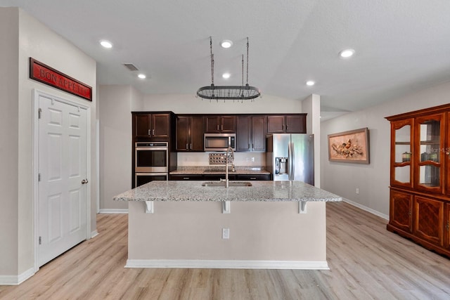 7302 Sunshine Bridge Ave, Gibsonton, FL 33534 - kitchen featuring appliances with stainless steel finishes, a breakfast bar, light wood-style floors, a kitchen island with sink, and vaulted ceiling