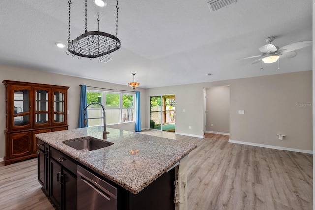 7302 Sunshine Bridge Ave, Gibsonton, FL 33534 - kitchen with dishwasher, light wood finished floors, a textured ceiling, an island with sink, and light stone countertops