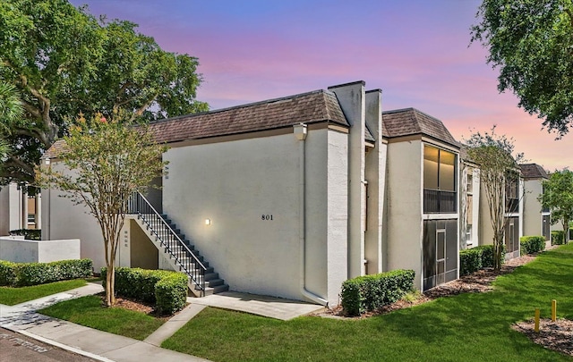 801 Russell Ln Unit 252, Brandon, FL 33510 - view of front facade with stucco siding, stairway, mansard roof, and a front yard