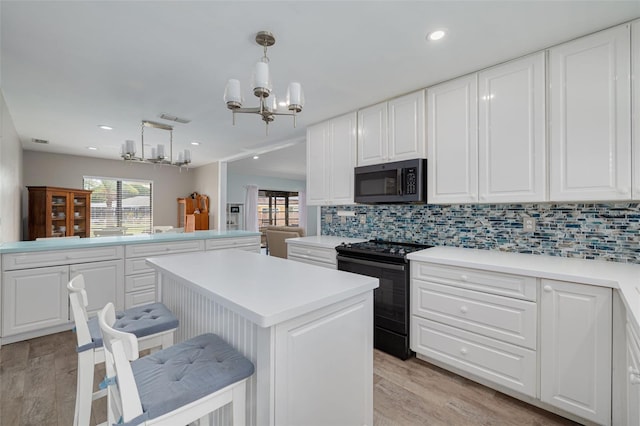 1913 Libby Ct, Holiday, FL 34690 - kitchen featuring black electric range, a chandelier, light wood-style flooring, decorative backsplash, and recessed lighting