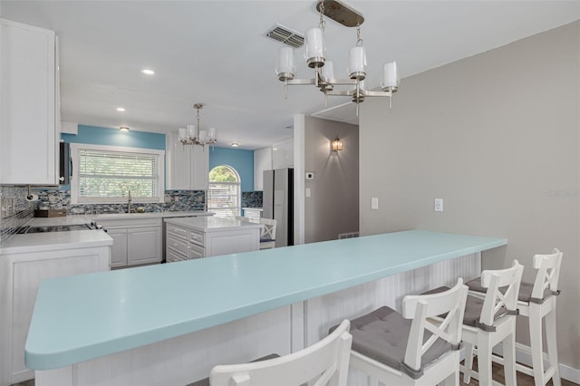 1913 Libby Ct, Holiday, FL 34690 - kitchen featuring a chandelier, decorative backsplash, freestanding refrigerator, a sink, and a breakfast bar