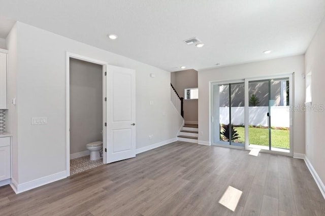 503 W Warren Ave Unit 1, Tampa, FL 33624 - unfurnished living room featuring stairway, light wood-type flooring, baseboards, and recessed lighting