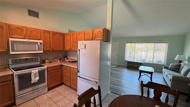 6405 Klaus Ct, Port Charlotte, FL 33981 - kitchen with electric range oven, stainless steel microwave, freestanding refrigerator, open floor plan, and light countertops