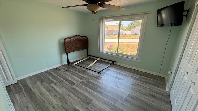6405 Klaus Ct, Port Charlotte, FL 33981 - unfurnished bedroom with wood finished floors, baseboards, ceiling fan, and a textured ceiling
