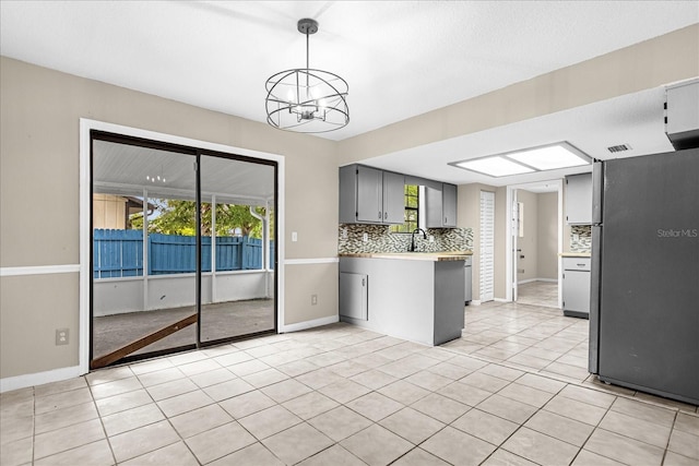 3331 Lime Tree Dr, Edgewater, FL 32141 - kitchen with a chandelier, backsplash, a peninsula, gray cabinets, and light countertops