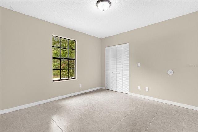 3331 Lime Tree Dr, Edgewater, FL 32141 - unfurnished bedroom featuring a closet, a textured ceiling, tile patterned flooring, and baseboards