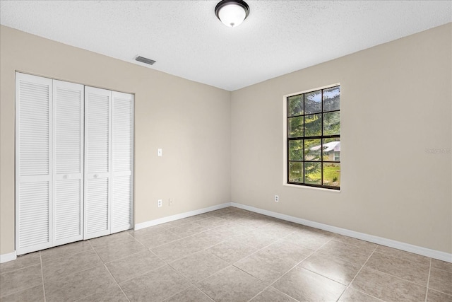 3331 Lime Tree Dr, Edgewater, FL 32141 - unfurnished bedroom featuring a textured ceiling, a closet, baseboards, and tile patterned floors