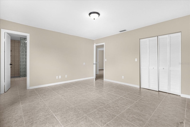 3331 Lime Tree Dr, Edgewater, FL 32141 - unfurnished bedroom featuring baseboards, a closet, light tile patterned flooring, and connected bathroom
