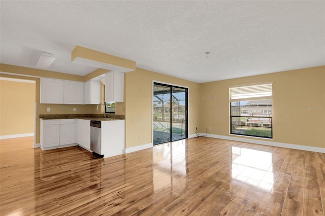 910 SE 23rd Pl, Cape Coral, FL 33990 - kitchen featuring stainless steel dishwasher, light wood finished floors, a sink, white cabinets, and a textured ceiling