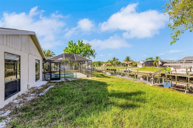 910 SE 23rd Pl, Cape Coral, FL 33990 - view of grassy yard with a water view, glass enclosure, and a boat dock