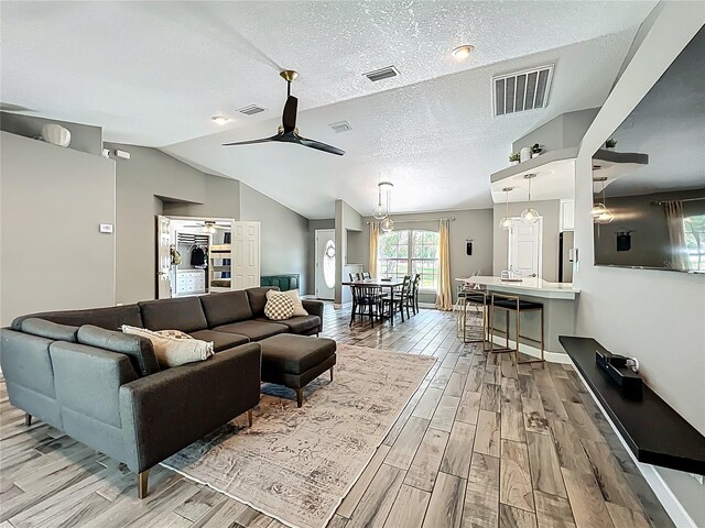 1199 E Mckinley St, Hernando, FL 34442 - living area with light wood-style flooring, ceiling fan, vaulted ceiling, and a textured ceiling