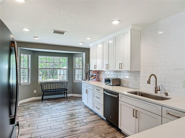 1199 E Mckinley St, Hernando, FL 34442 - kitchen with appliances with stainless steel finishes, a sink, light countertops, baseboards, and white cabinetry
