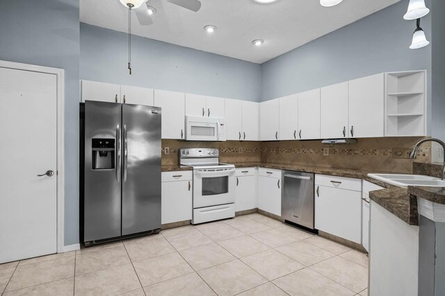 2516 New Haven Cir, Sun City Center, FL 33573 - kitchen featuring stainless steel appliances, a sink, dark countertops, open shelves, and decorative backsplash