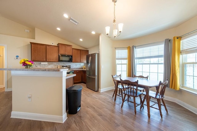 3642 Fantasy Way, Brooksville, FL 34604 - kitchen featuring stainless steel appliances, brown cabinetry, a chandelier, baseboards, and vaulted ceiling