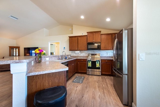 3642 Fantasy Way, Brooksville, FL 34604 - kitchen with stainless steel appliances, a sink, vaulted ceiling, light wood finished floors, and a peninsula