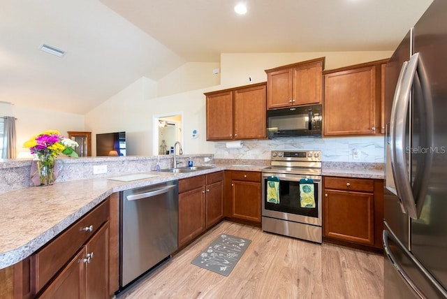 3642 Fantasy Way, Brooksville, FL 34604 - kitchen with appliances with stainless steel finishes, vaulted ceiling, a sink, brown cabinets, and light wood-type flooring