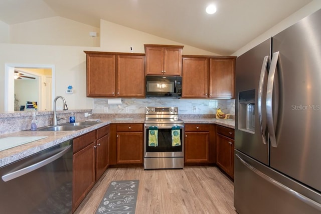 3642 Fantasy Way, Brooksville, FL 34604 - kitchen featuring appliances with stainless steel finishes, lofted ceiling, light wood-style flooring, a sink, and brown cabinets
