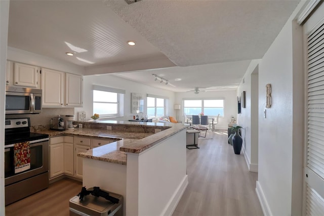 1270 Gulf Blvd Unit 1901, Clearwater Beach, FL 33767 - kitchen with appliances with stainless steel finishes, a peninsula, open floor plan, light wood-style floors, and stone counters