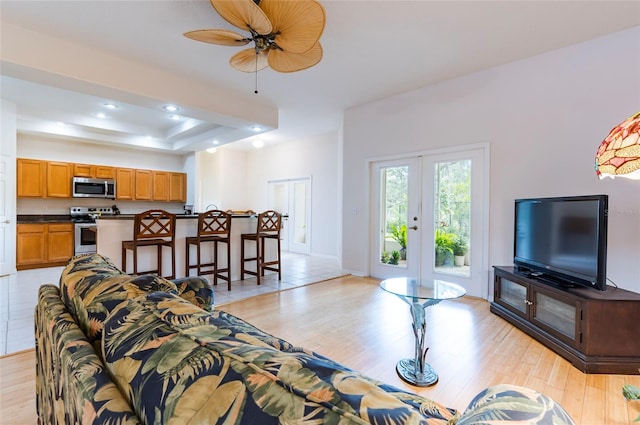 9908 Alafia River Ln, Gibsonton, FL 33534 - living room with light wood-style floors, french doors, ceiling fan, recessed lighting, and a tray ceiling