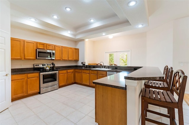 9908 Alafia River Ln, Gibsonton, FL 33534 - kitchen with appliances with stainless steel finishes, recessed lighting, a raised ceiling, a kitchen bar, and a peninsula