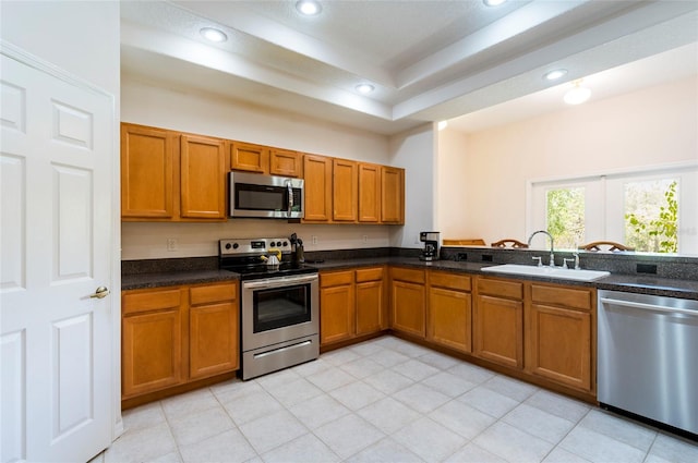9908 Alafia River Ln, Gibsonton, FL 33534 - kitchen with appliances with stainless steel finishes, a sink, brown cabinets, recessed lighting, and a tray ceiling